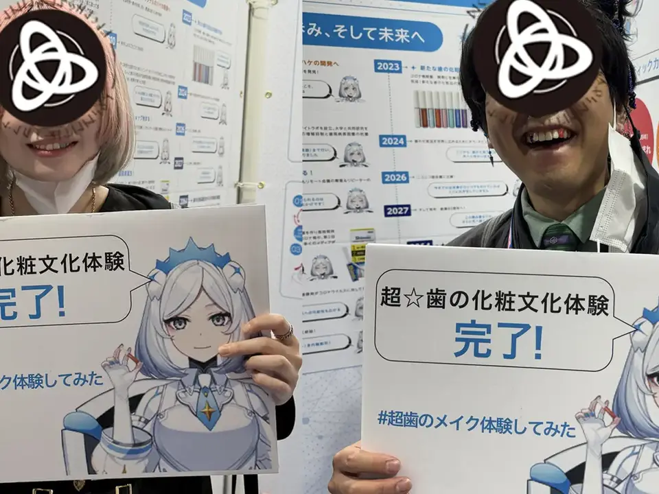 イベントで歯の化粧文化を体験し、体験完了ボードを持つ参加者